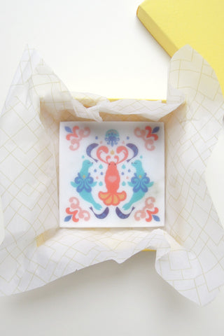 The Lobester Quadrille marble coaster inside its packaging, a yellow box. Designed by Chiara Aliotta.