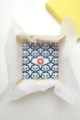 Polyphemus marble coaster inside its yellow paper box. Designed by Chiara Aliotta.